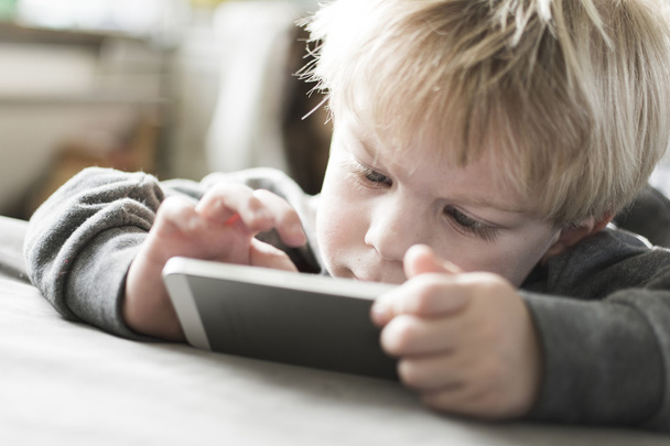 Boy playing games on smartphone - Фото, изображение