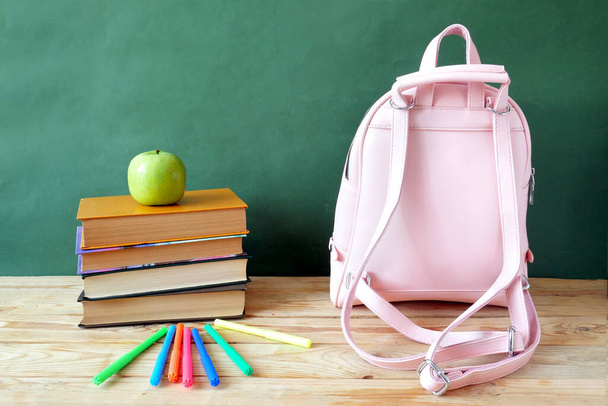 Βιβλίο σωρό με μήλο, σφαίρα, μολύβια και ξύστρα στο μαυροπίνακα του σχολείου. Έννοια ημέρας δασκάλου - Φωτογραφία, εικόνα