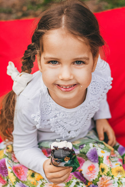Kaunis pieni tyttö syö jäätelöä kesällä kirkas tausta - Valokuva, kuva