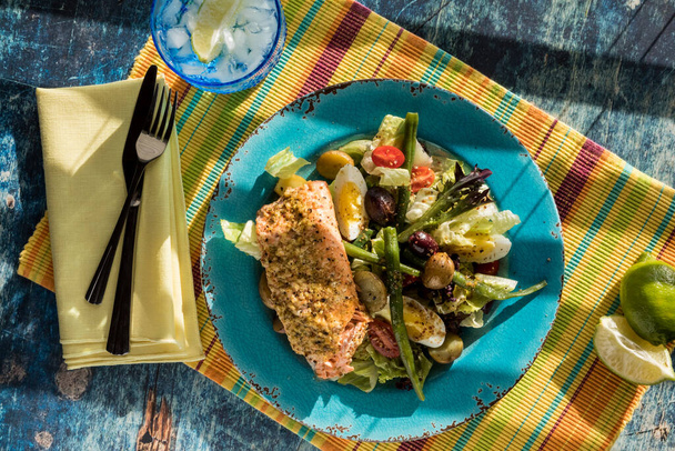 Салат из Никуазы с лососем на бирюзовой тарелке, готовый к употреблению. - Фото, изображение