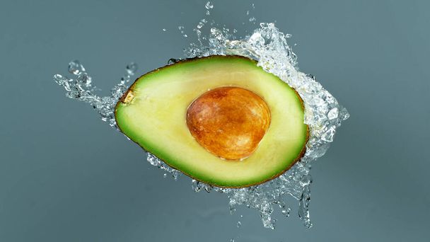 Freeze motion of sliced avocado with splashing water - Foto, Imagem