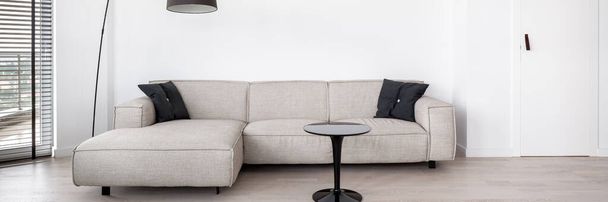 Panorama of simple living room with stylish beige corner sofa and modern black coffee table - Zdjęcie, obraz