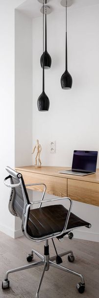 Vertical panorama of simple home office corner with wooden desk, comfortable chair and pendant lighting - Photo, image