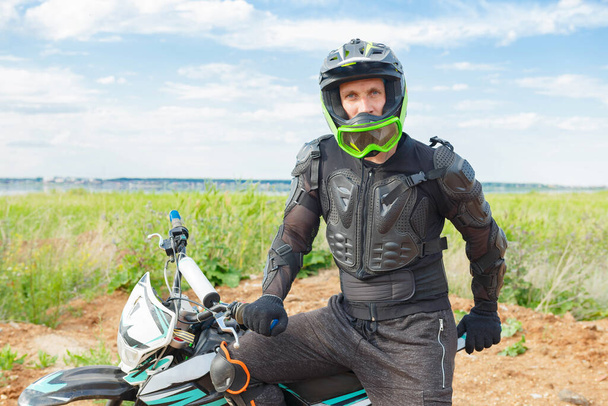 A man in motorcycle equipment sits on an enduro motorcycle. Motocross rider in action. Motocross sport. Extreme off-road race. Hard enduro motorbike. - 写真・画像