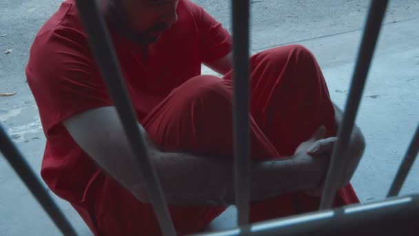 Gevangene zit en wacht achter tralies, gevangenis of gevangenis detentiecentrum - Video