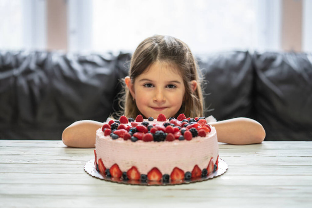 Маленькая девочка день рождения торт. Домашний торт с ягодами. Торт с клубникой, ежевикой, черникой и малиной на столе - Фото, изображение
