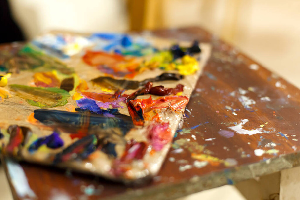 Close-up of an easel with paints, the artist paints a brush. Painting a picture - Photo, Image