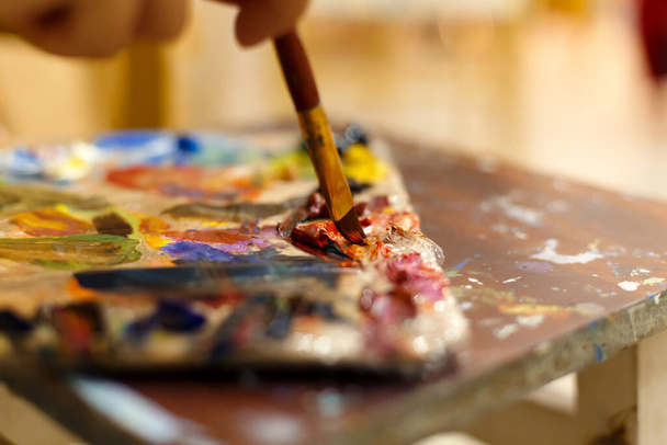 Close-up of an easel with paints, the artist paints a brush. Painting a picture - Фото, зображення