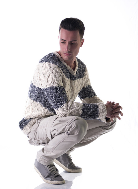 Good looking young man with winter sweater, sitting on his heels - Фото, зображення