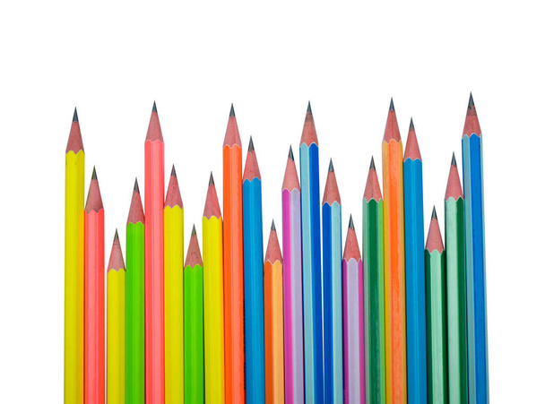 Many different colored wood pencil crayons scattered in a line on a white paper background - Photo, Image