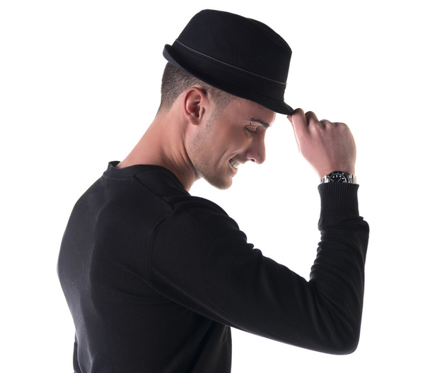 Profile shot of young man smiling, touching fedora hat - Foto, Imagem