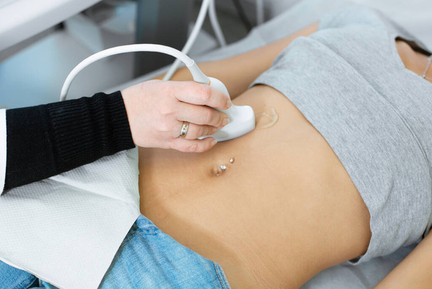 The doctor conducts an ultrasound diagnosis of the patient abdomen and internal organs. - Foto, immagini