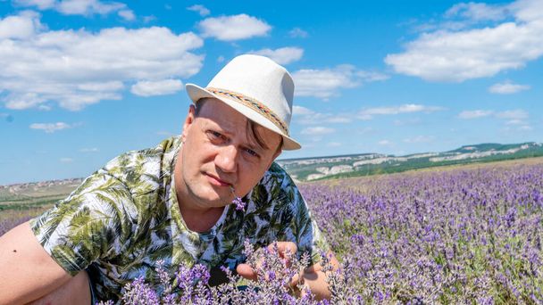 A smiling guy in a lilac box having a joyful face sits in a cap against a blue sky with a blue sky - Fotografie, Obrázek