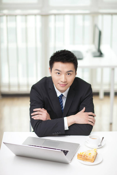 	Portrait of businessman sitting at desk by laptop	 - Фото, зображення