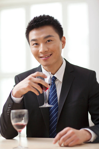 Ritratto di uomo d'affari alla scrivania con un bicchiere di vino - Foto, immagini