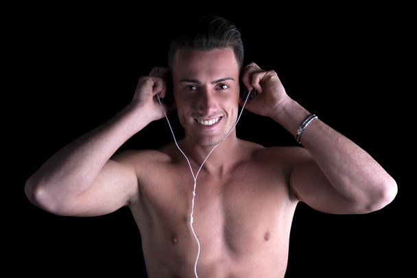 Athletic shirtless man listening to music on headphones - Foto, Imagem