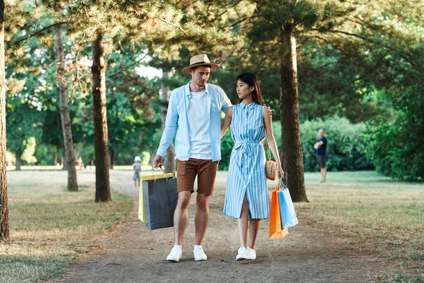 young couple with shopping bags walking  in the park.  - Fotoğraf, Görsel
