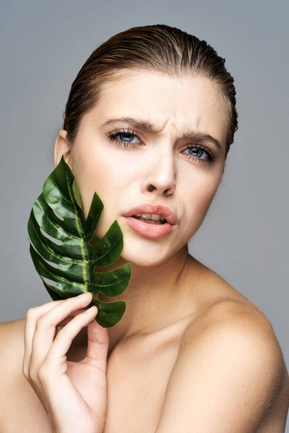 Young beautiful woman posing  with  leaf in studio - Valokuva, kuva
