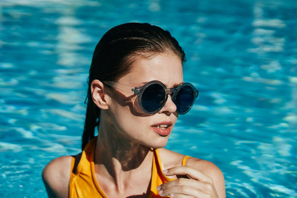 Güneş gözlüklü genç bir kadın havuzda dinleniyor.   - Fotoğraf, Görsel