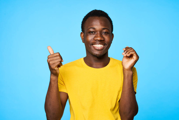 Young man  with thumb up   isolated on blue background - Фото, изображение