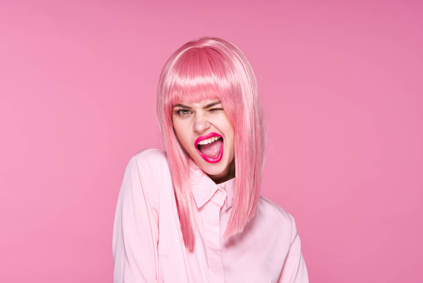 Studio shot. Young girl in pink wig winking  on pink background - Photo, Image