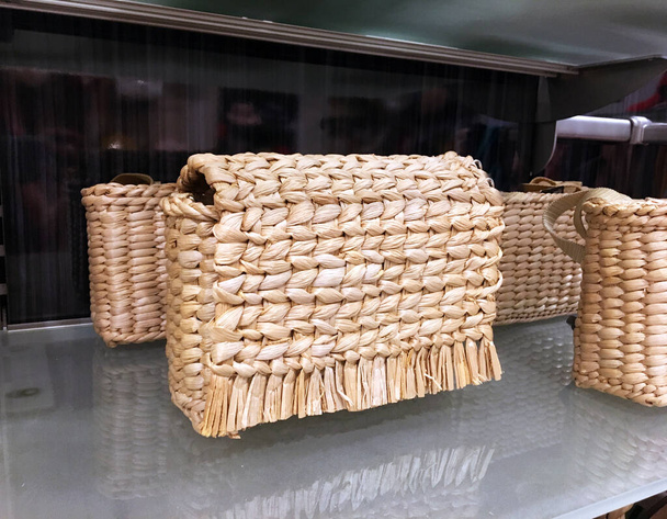 Straw Clutch Purses  on shelf. Elegant bag in a showcase of a luxury store.  Fashion trend 2021. Fashionable clutch of envelope shape. Fashion women accessories. Fashion concept - Photo, Image