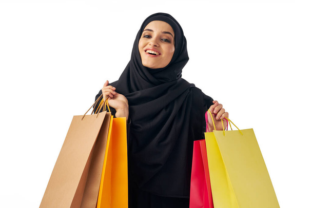 Youg muslim woman in hijab   holding shopping bags in studio         - Фото, изображение