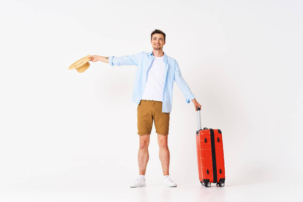 Studio shot of young man tourist with suitcase and hat  - Photo, Image