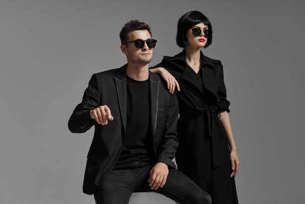 young beautiful stylish couple  in sunglasses  posing  in studio, isolated - Photo, Image