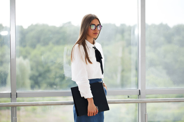 girl in a shirt businessman holding a folder in a white office by the window - Fotografie, Obrázek