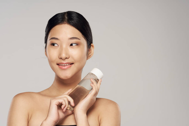 Jovem bela mulher asiática com produto de cuidados com a pele em estúdio no fundo isolado - Foto, Imagem