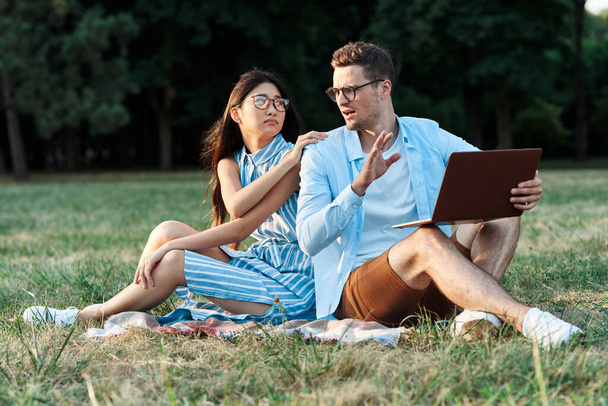 jeunes étudiants avec ordinateur portable assis sur la pelouse  - Photo, image