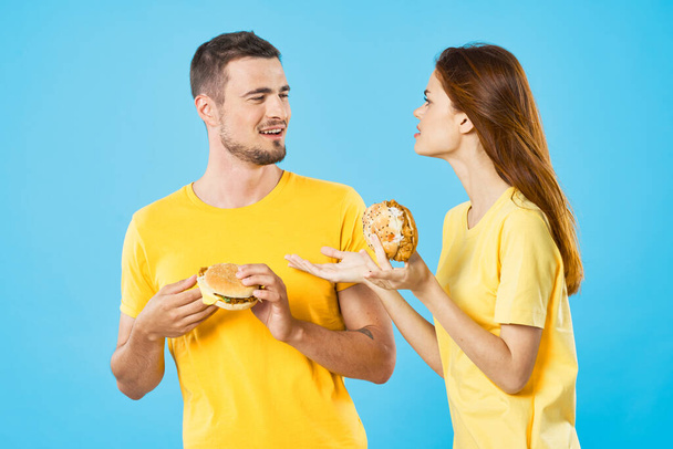 Joven hermosa pareja comiendo hamburguesas. Captura de estudio - Foto, imagen