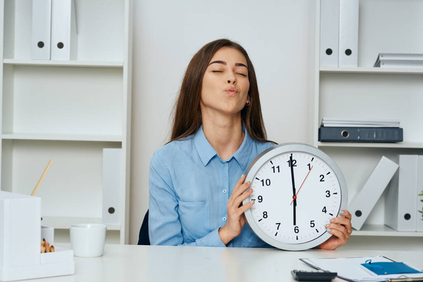 Young beautiful businesswoman sitting at desk in the office with clock  - Foto, Imagem
