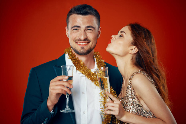Joven hermosa pareja celebrando Año Nuevo besándose sobre fondo rojo - Foto, Imagen