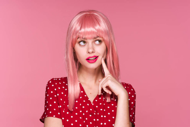 Στιγμιότυπο. Νεαρό κορίτσι με ροζ περούκα σκέφτεται σε ροζ φόντο - Φωτογραφία, εικόνα