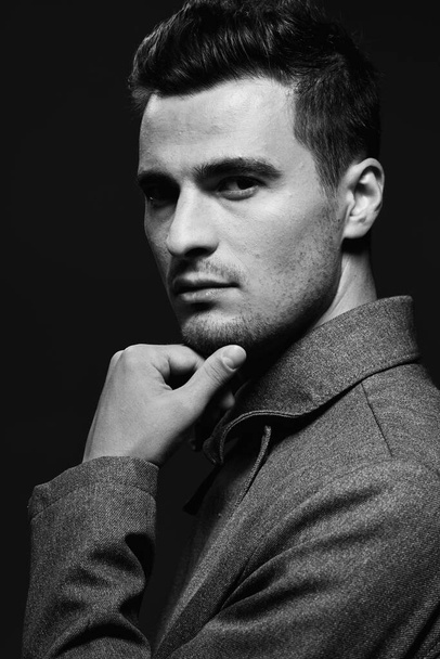 Studio shot. Young handsome man in coat, black and white  - Fotografie, Obrázek