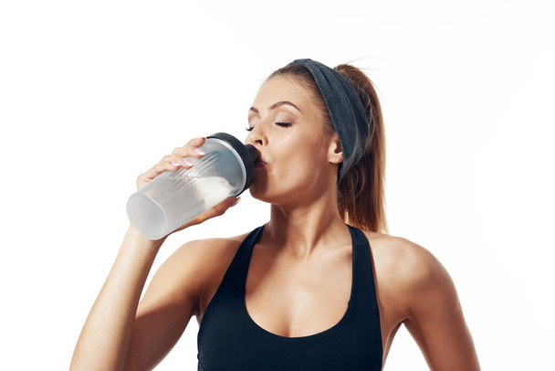 Young fit woman  drinking   energy cocktail  on isolated background - Photo, Image