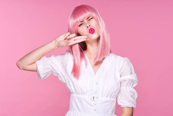 Studio shot. Young girl in pink wig gestuting  on pink background - Foto, afbeelding