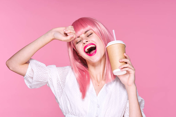 Sudio colpo di bella donna in parrucca rosa in possesso di tazza di caffè su sfondo rosa - Foto, immagini