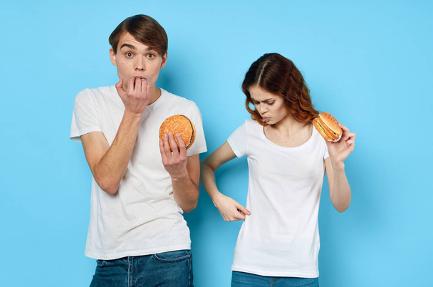 mladý muž a žena jíst hamburgery ve studiu  - Fotografie, Obrázek