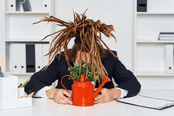 Mladý podnikatel sedí v kanceláři s rostlinou - Fotografie, Obrázek