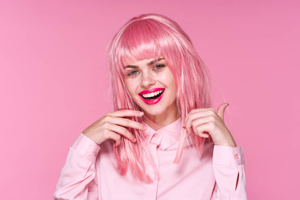Studio záběr. Mladá dívka v růžové paruce s úsměvem na růžovém pozadí - Fotografie, Obrázek