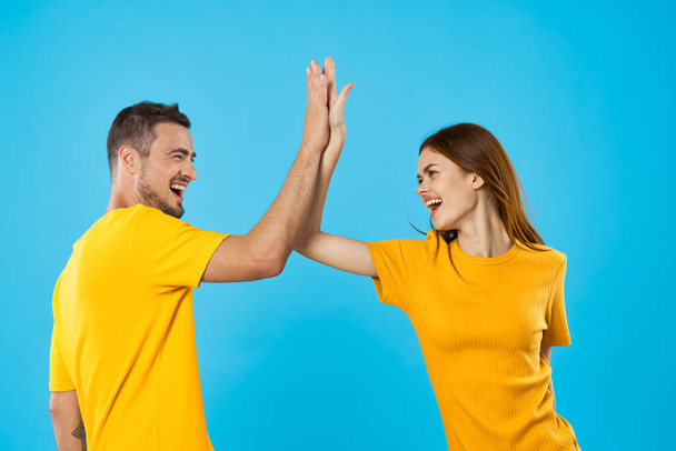 junge Frau und Mann geben High Five auf blauem Hintergrund  - Foto, Bild