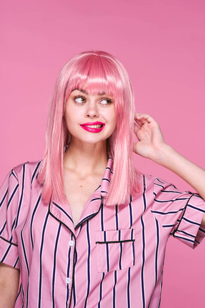 Sudio shot di bella donna in parrucca rosa in ascolto su sfondo rosa - Foto, immagini