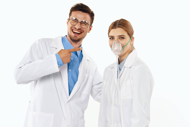 Νεαρός γιατρός και νοσοκόμα στο στούντιο, απομονωμένο υπόβαθρο. γυναίκα με εισπνευστήρα  - Φωτογραφία, εικόνα