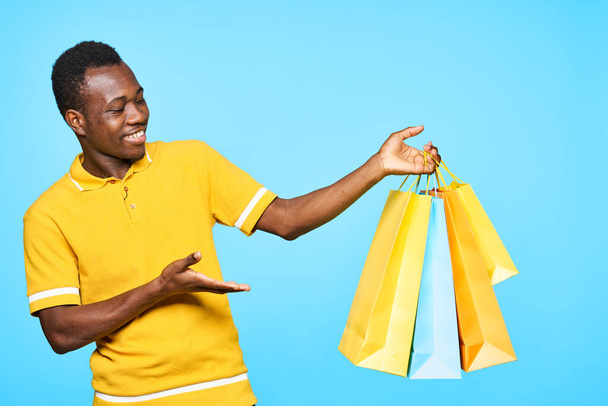 young afrivan man with shopping bags on blue background  - Fotoğraf, Görsel