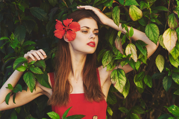 Jeune belle femme posant avec des fleurs dans ses cheveux regardant loin  - Photo, image
