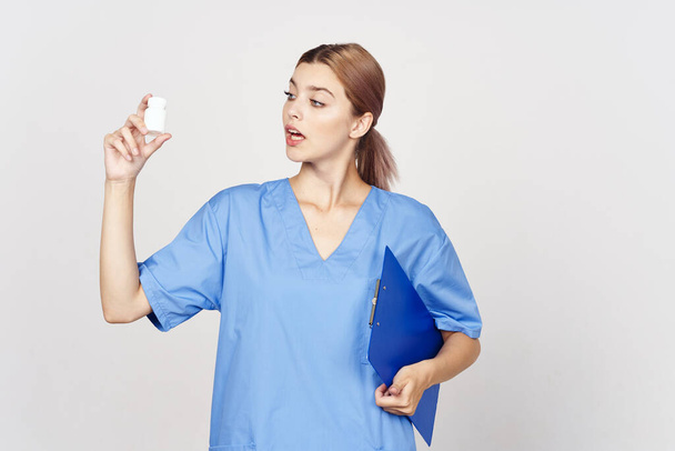 Στιγμιότυπο. Νεαρή γυναίκα γιατρός κρατώντας χάπια σε λευκό φόντο - Φωτογραφία, εικόνα