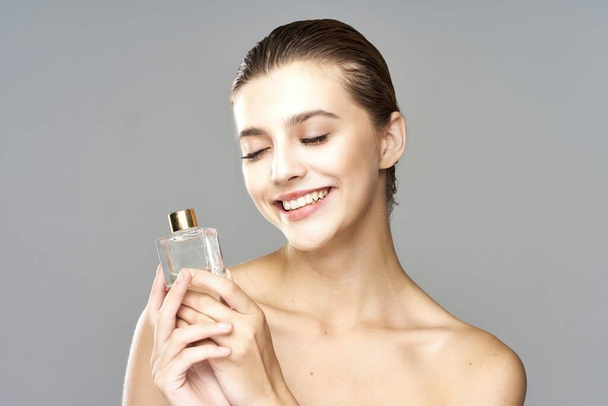 portret młodej pięknej kobiety z butelką perfum, odizolowany  - Zdjęcie, obraz